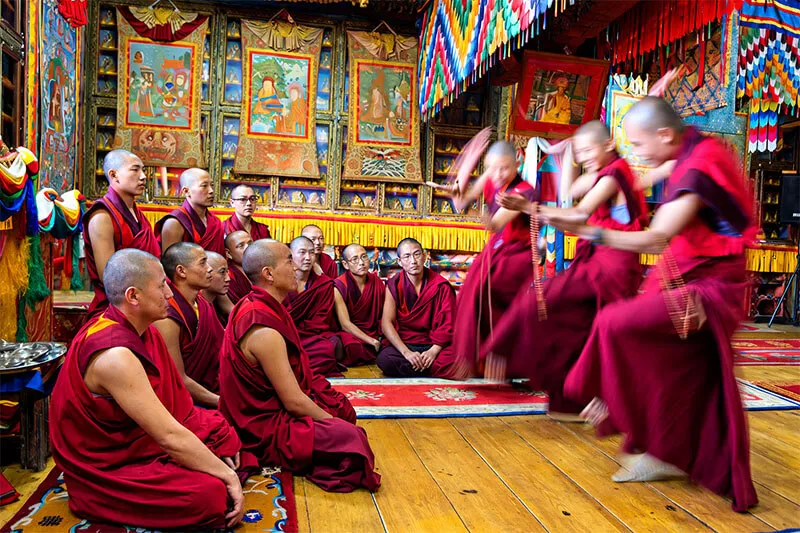 Monks in red robes chanting inside a Bhutanese temple