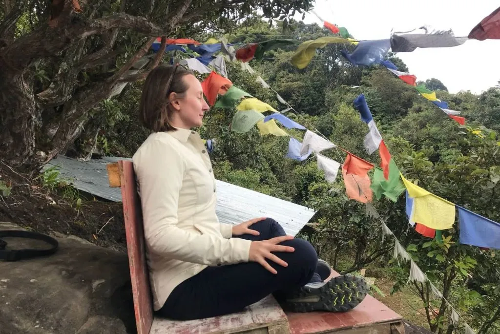 Traveller meditating beside prayer flags in Bhutan